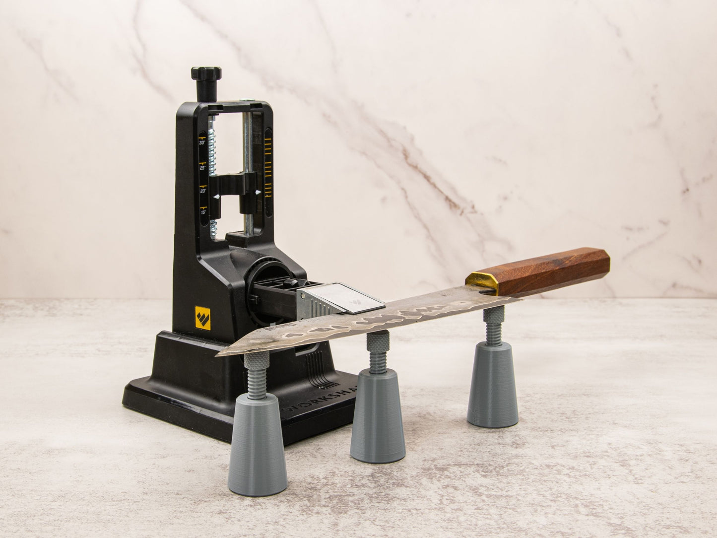 Work Sharp Precision Adjust knife sharpening system with a chef knife supported by three adjustable knife edge supports, aligned for stable sharpening.