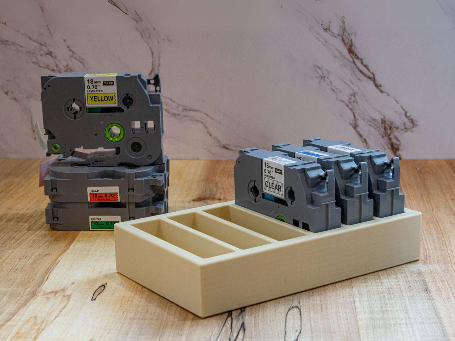 Brother 18mm label tape organizer holding multiple color-coded laminated cartridges next to stacked loose tapes for size comparison.