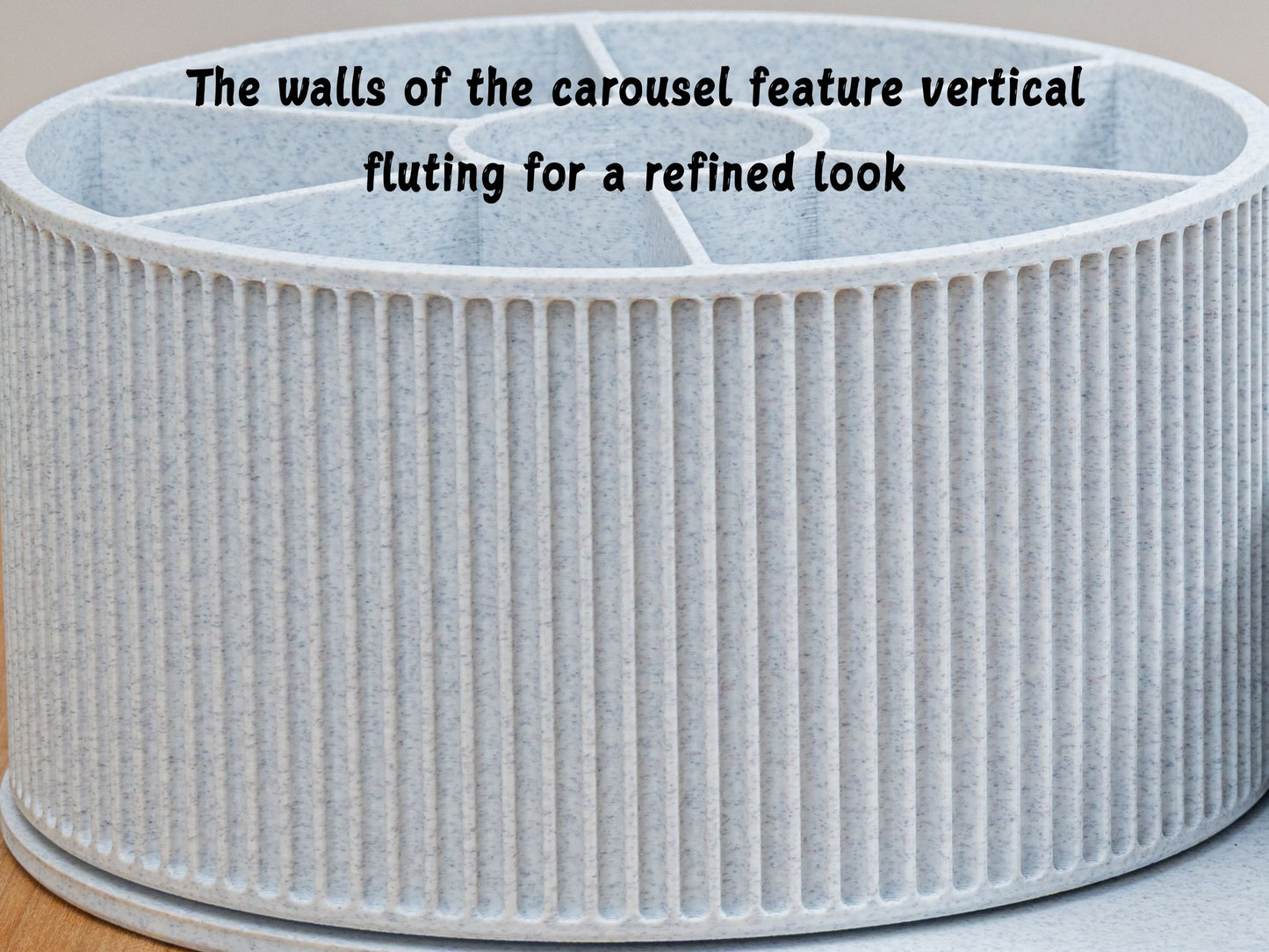Macro close-up of the round carousel’s exterior showing crisp vertical fluting and a clean, speckled light-gray finish, emphasizing refined texture and build quality; on-image text notes the vertical fluting for a polished look.