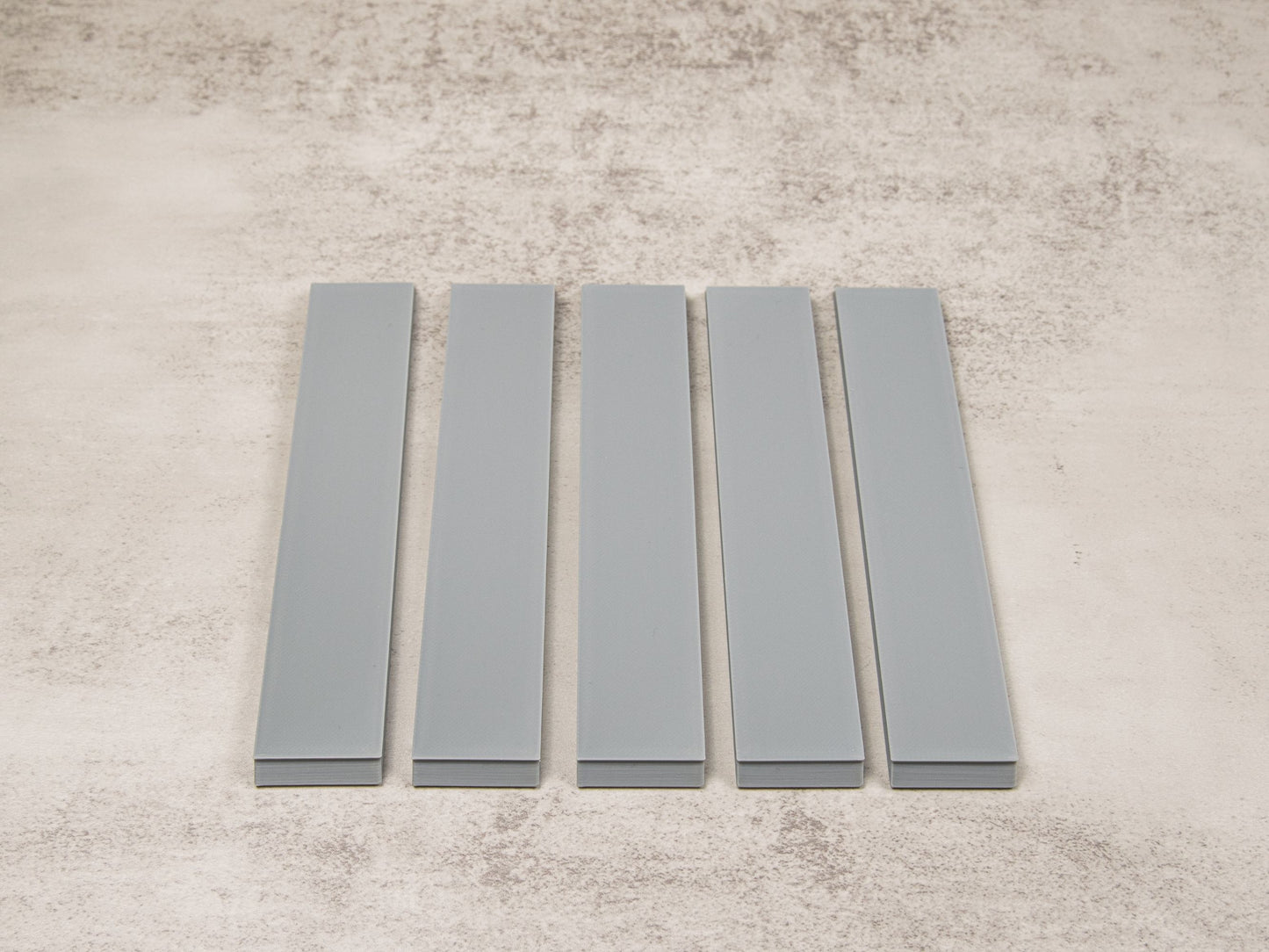 Top-down view of five lapping film blanks laid flat for sharpening stones, strops, or polishing films