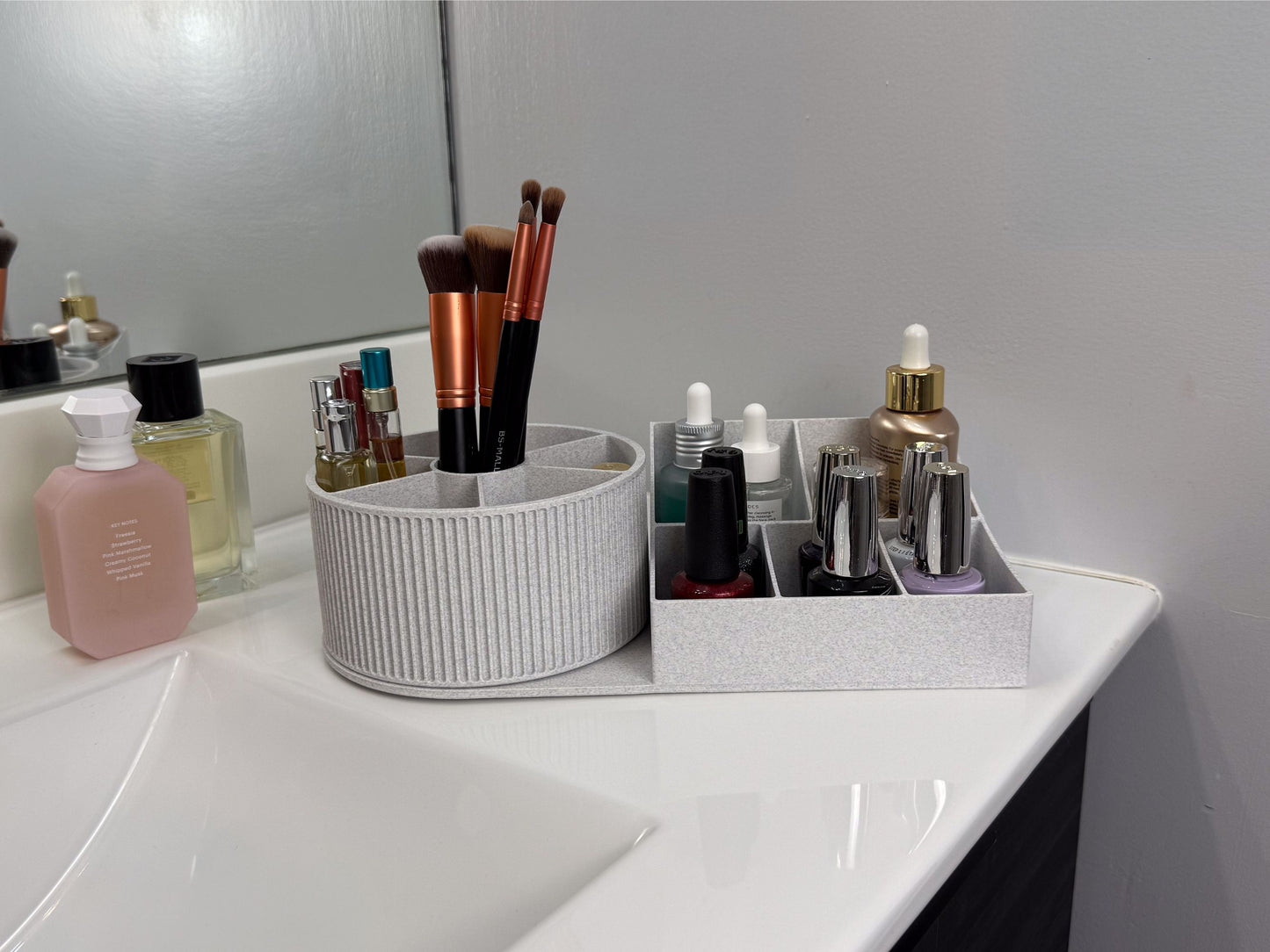Angled bathroom shot of the rotating beauty organizer on a sink counter; the round carousel holds makeup brushes and travel sprays, while the rectangular base stores serums and nail polishes; soft, neutral décor and mirror reflections emphasize a clean, organized vanity