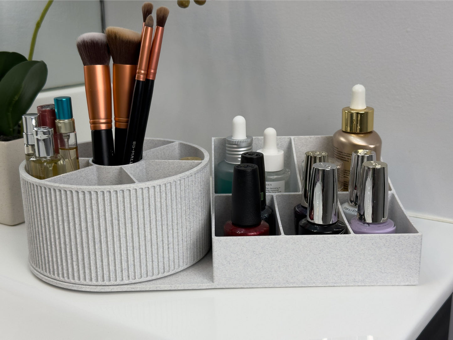 Close-up of the rotating beauty organizer loaded with daily essentials; the round top carousel shows six wedge compartments and a center well for tools, while the adjacent base displays two larger and three smaller sections for bottles and polishes.