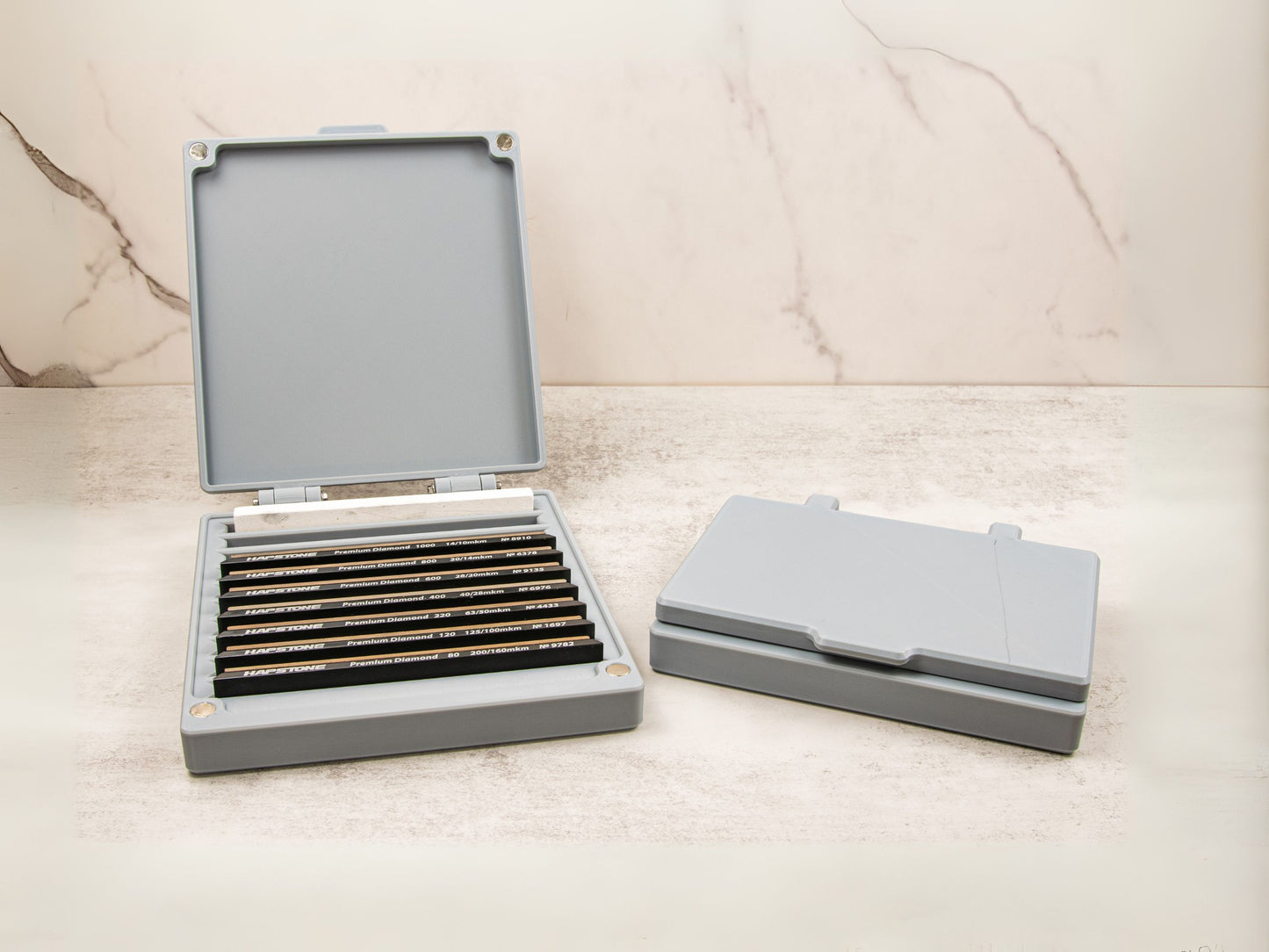 Side-by-side display of the sharpening stone case: one unit open with stones inside, and one closed for storage or travel.