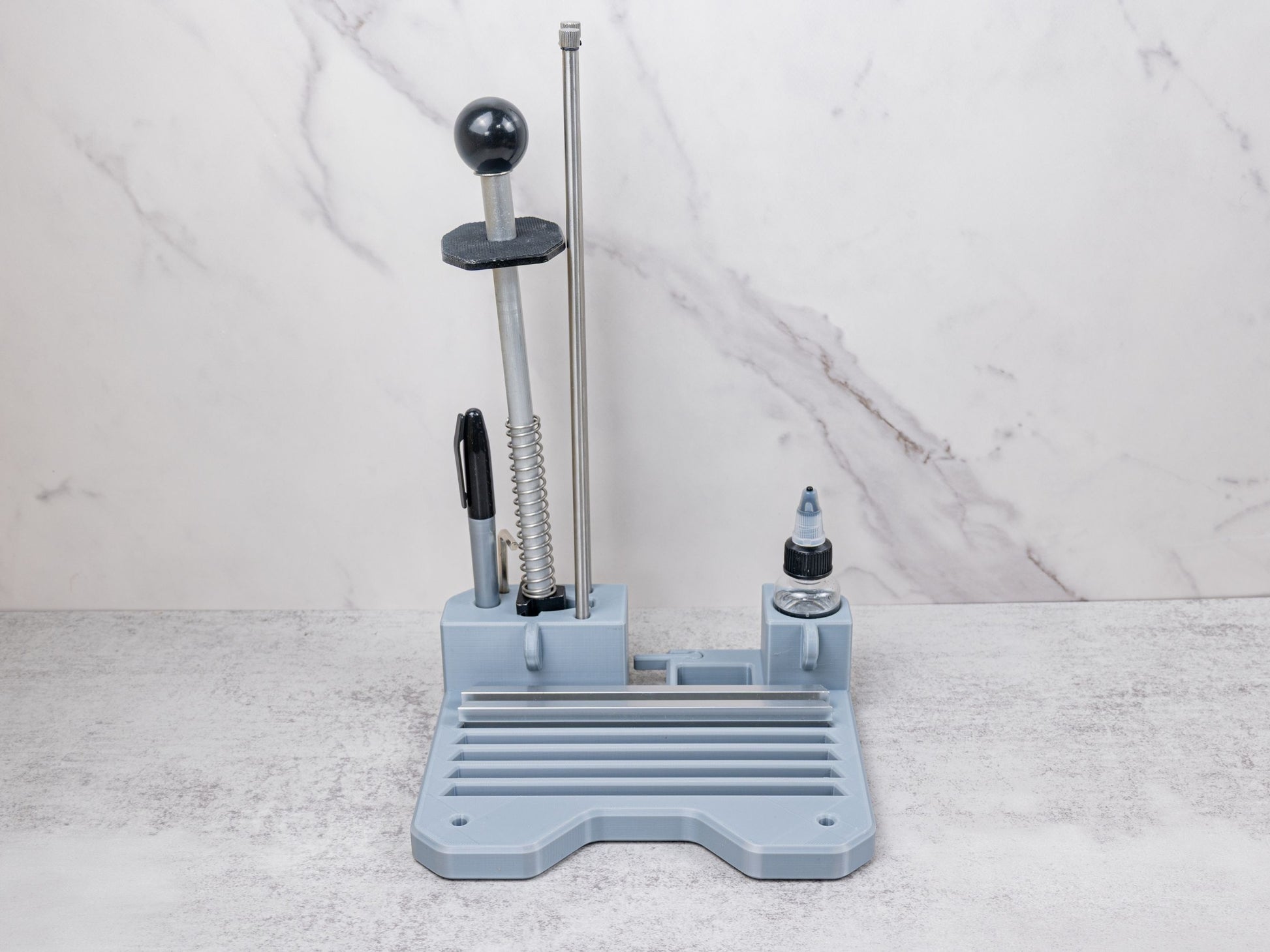 Organizer tray for the Xarilk Gen 3 Knife Sharpener shown fully loaded with accessories, including guide rods, stone holder, black marker, mineral oil bottle, and empty stone slots ready for sharpening stones.